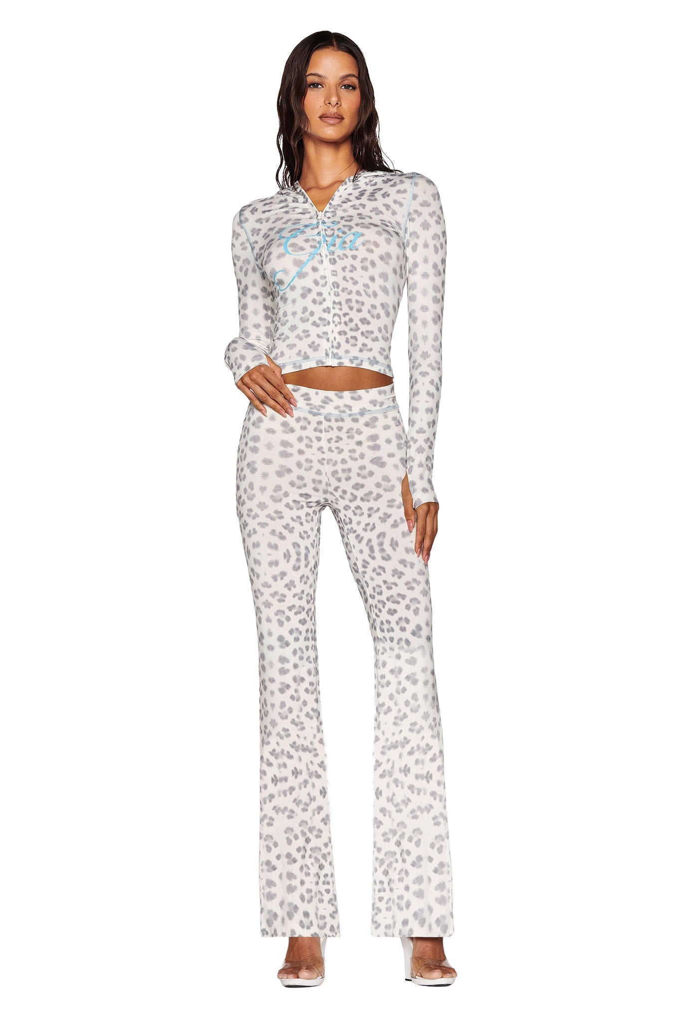 A person is confidently posing with one hand on their hip, wearing a coordinated outfit featuring the BLARE HOODIE - SNOW LEOPARD : WINTER WILD CARD and matching flared pants from I.AM.GIA, all against a plain white background.