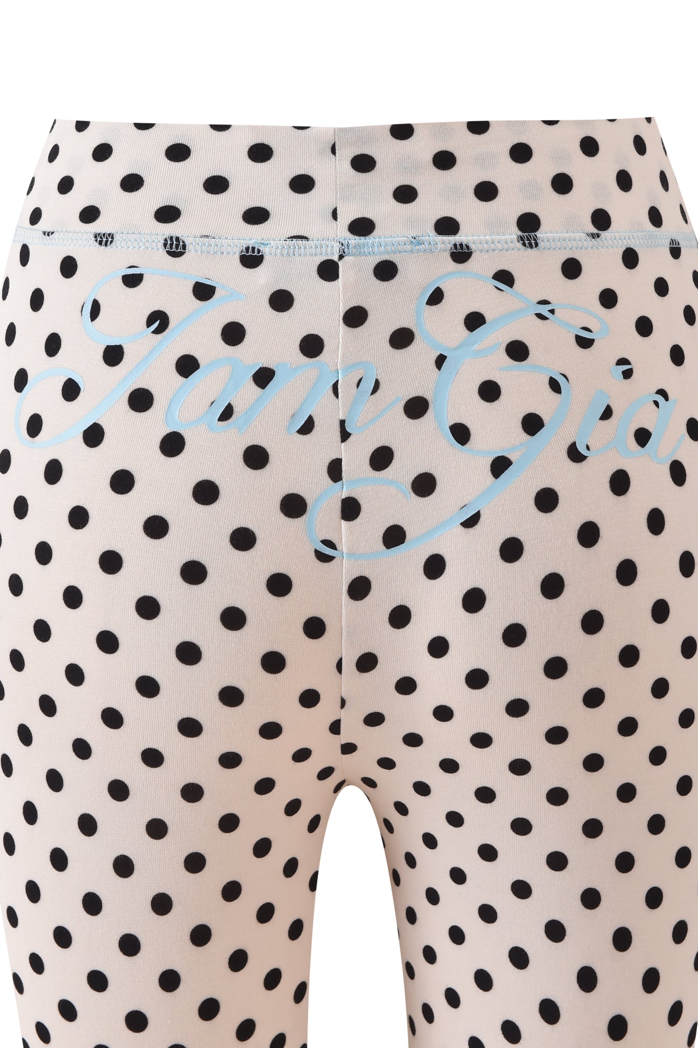 Close-up of BLARE TRACKPANT - CREAM POLKA DOT by I.AM.GIA, showcasing cream leggings with black polka dots and "Tara Gia" in light blue cursive across the back waistband.