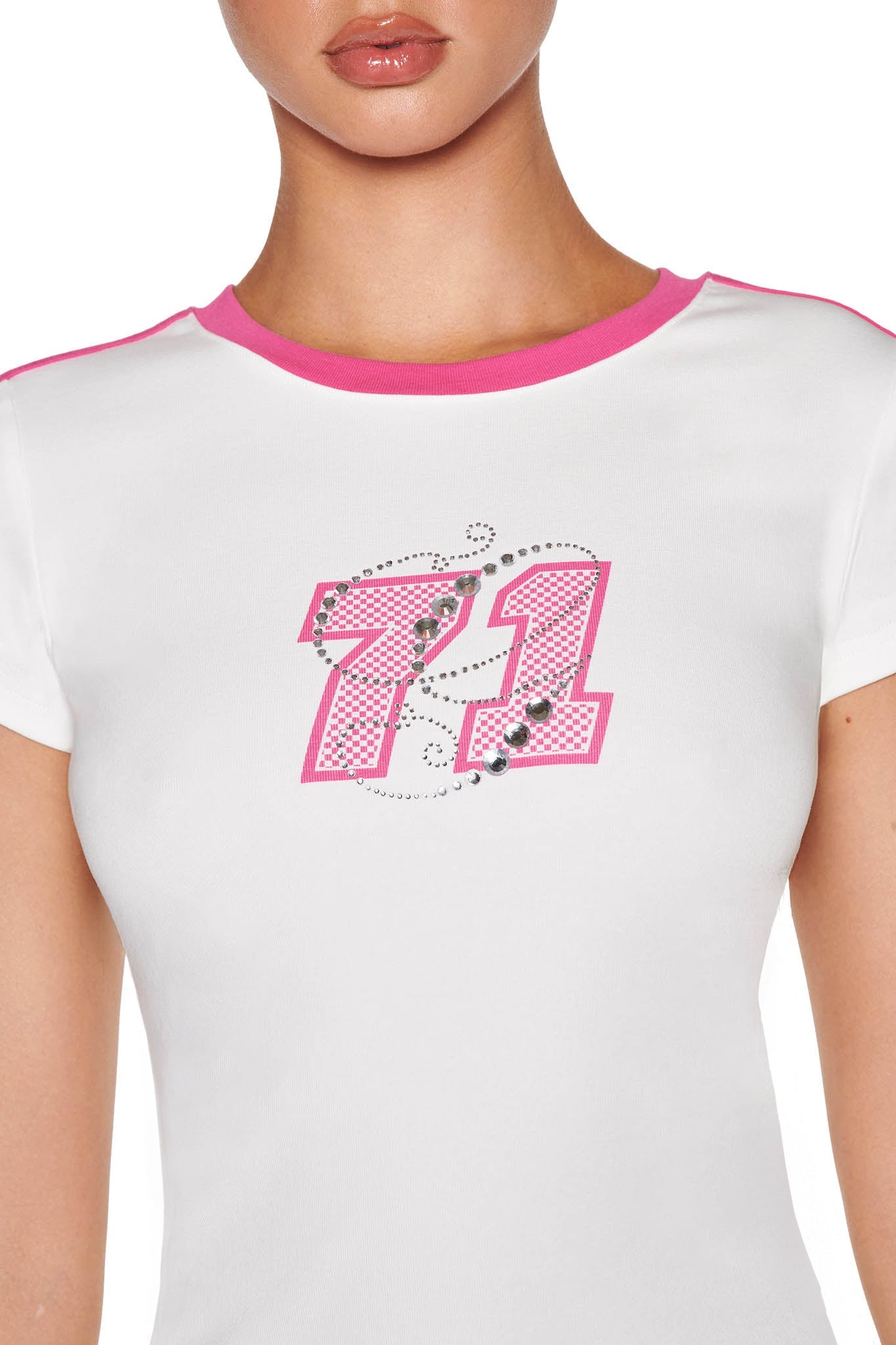 A person wearing the I.AM.GIA JENNIE TOP in WHITE: HOT PINK, a custom print baby tee with a bodycon fit, pink-trimmed sleeves, and rhinestone embellishment featuring the number "21" on the front. Their face is not fully visible.