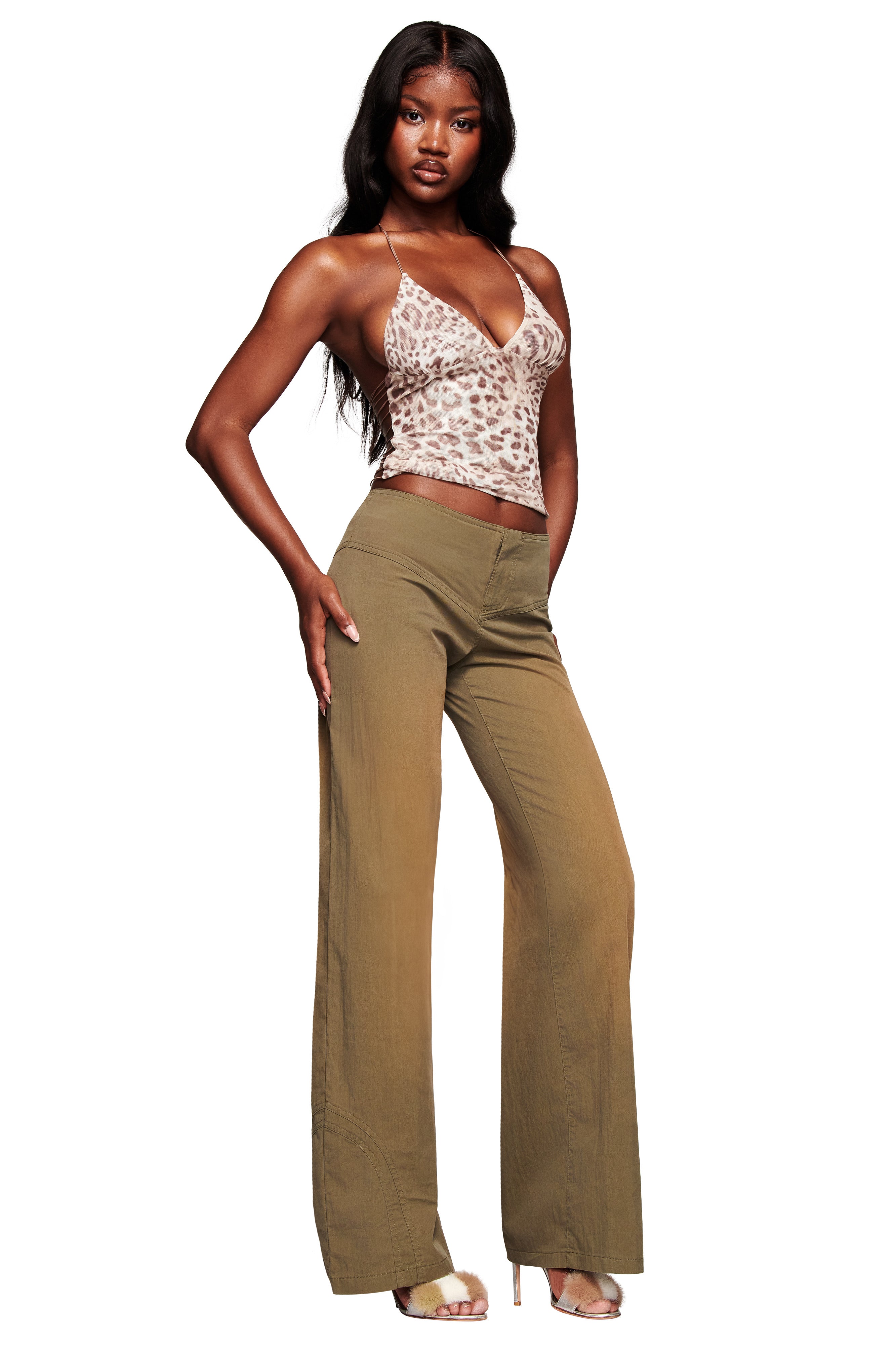 A woman stands confidently against a white background, wearing I.AM.GIA's SEQUOIA PANT in army green with a wide-leg fit, paired with a light animal-print camisole and beige open-toe heels.