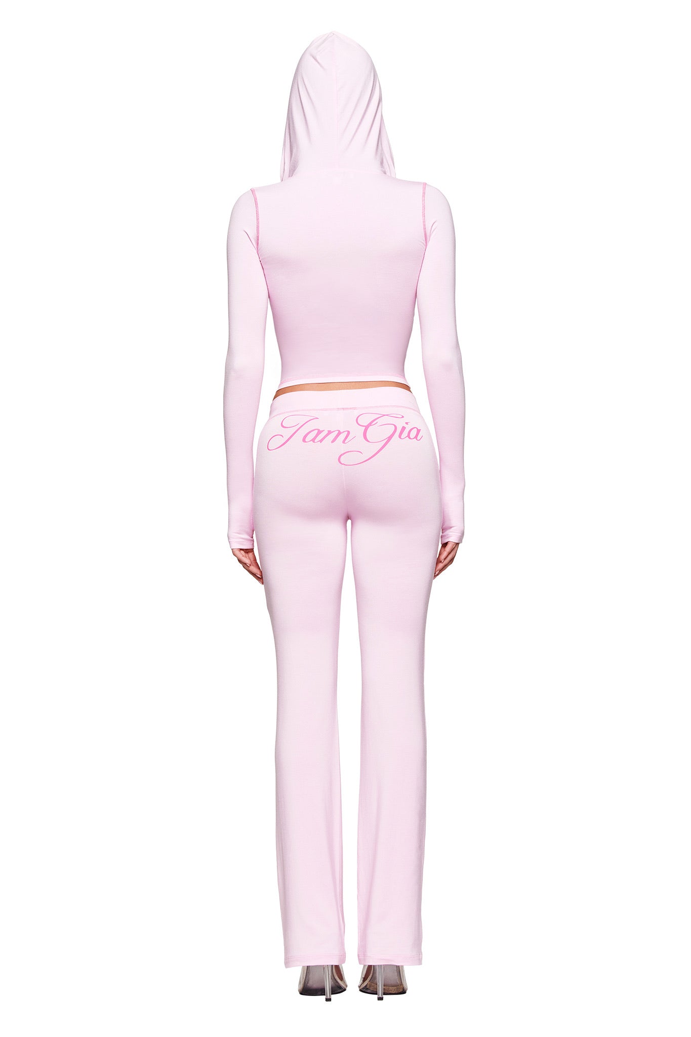 A person is seen from the back wearing a pastel pink, hooded crop top with matching BLARE TRACKPANT - PINK by I.AM.GIA. "I.AM.GIA" is written in cursive on the trackpant’s waistband.