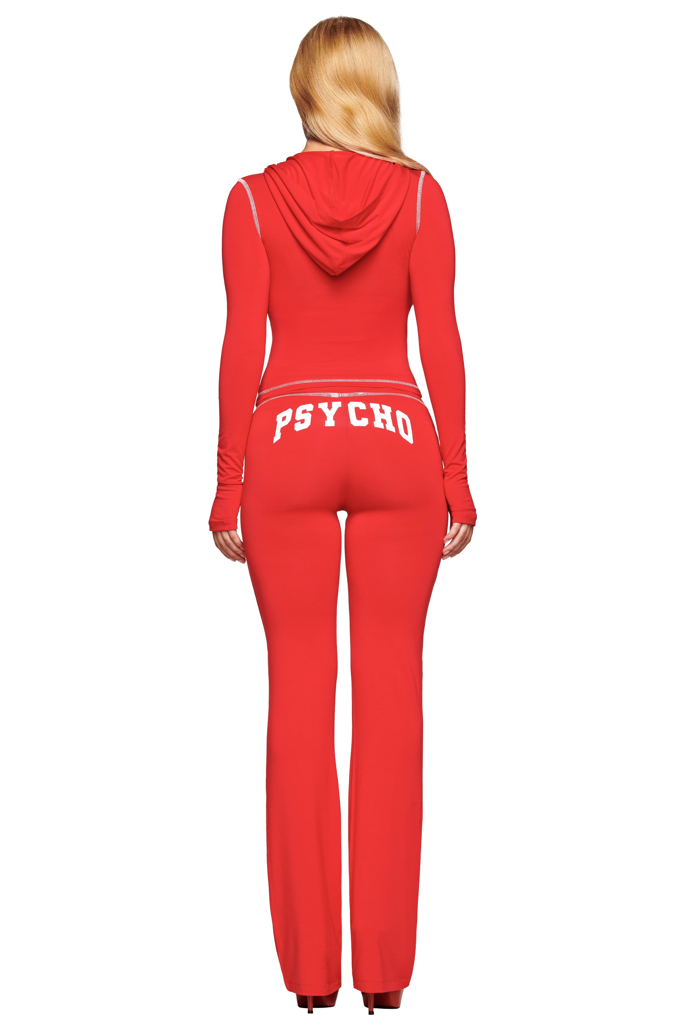 A person with long blonde hair is seen from behind wearing the I.AM.GIA BLARE HOODIE - RED : PSYCHO : SALSA tracksuit, featuring "PSYCHO" in bold white letters across the waistband.
