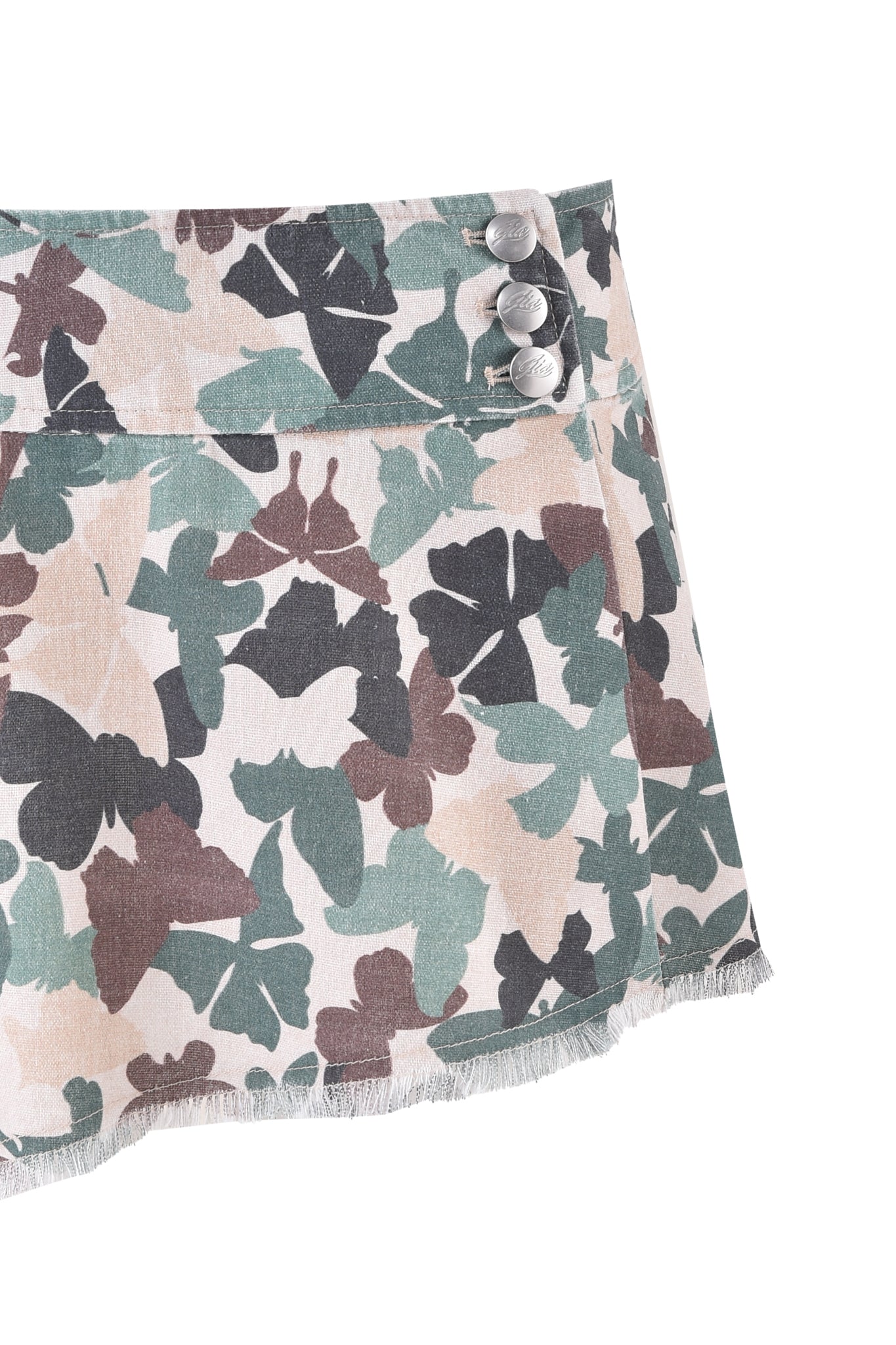 The EFFIE SKIRT - FLUTTER CAMO from I.AM.GIA features a teal, brown, and black butterfly camo print with a frayed edge and three buttons on the top right corner.
