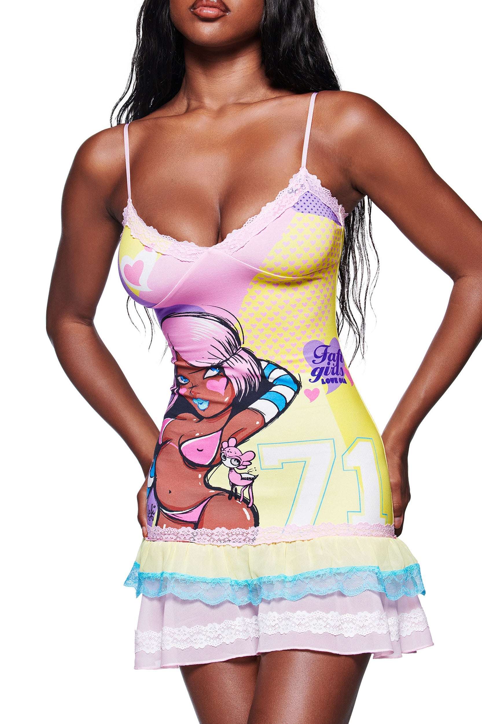 A woman wears the I.AM.GIA FAFI MINI DRESS - YELLOW, a colorful stretch jersey mini dress with cartoon graphics, lace trim, and layered hem ruffles.
