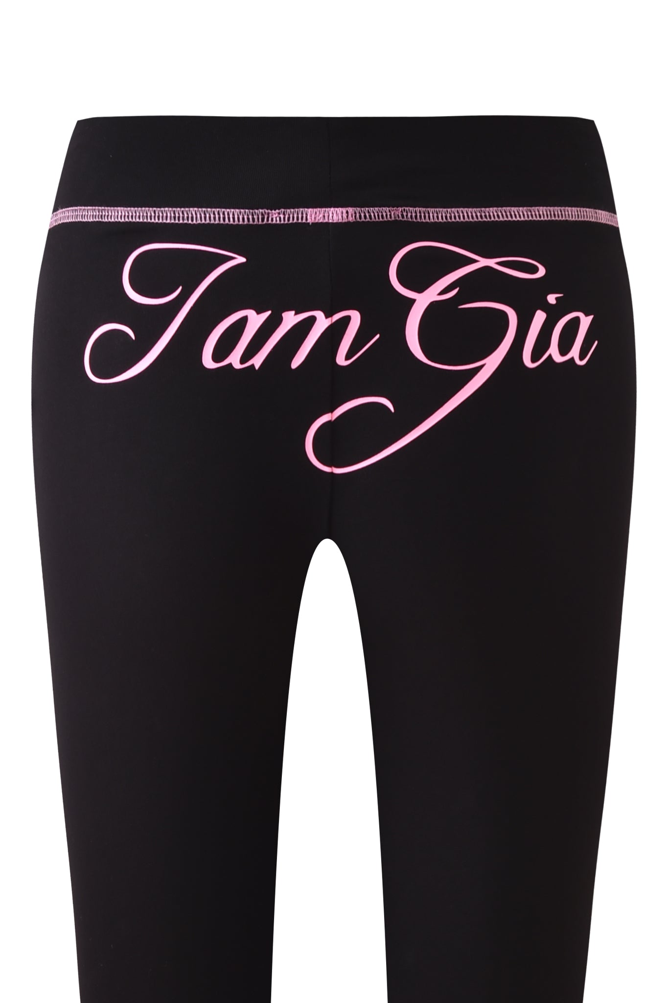 Close-up of the BLARE CAPRI - BLACK by I.AM.GIA, showcasing a bodycon fit and a bold pink I.AM.GIA logo in cursive across the waistband and upper back.