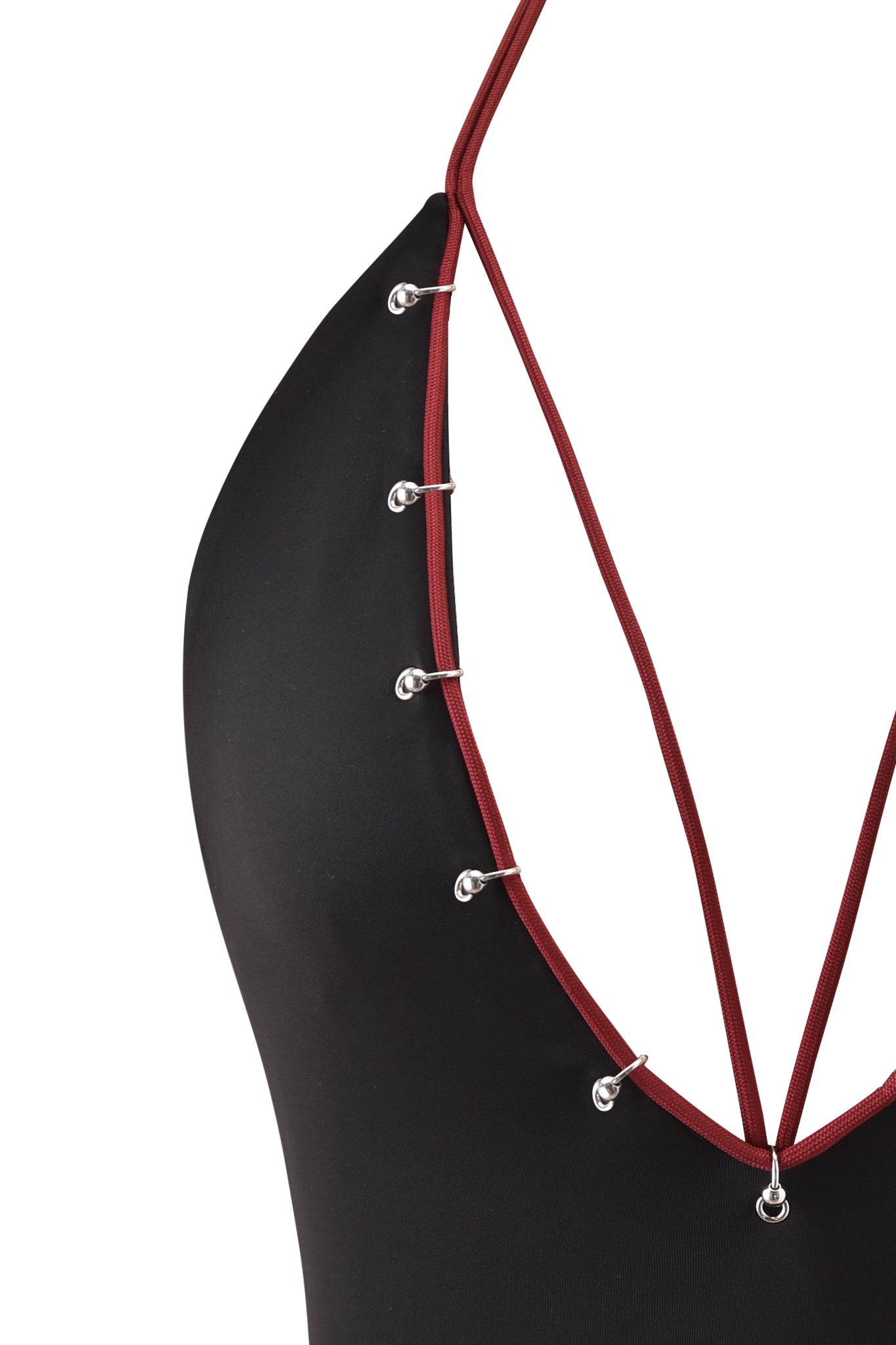 The ONYX TOP - BLACK by I.AM.GIA is a black halter top with a plunging neckline, featuring red-burgundy straps accented with silver metal eyelets along the front and a smooth, bodycon fit.