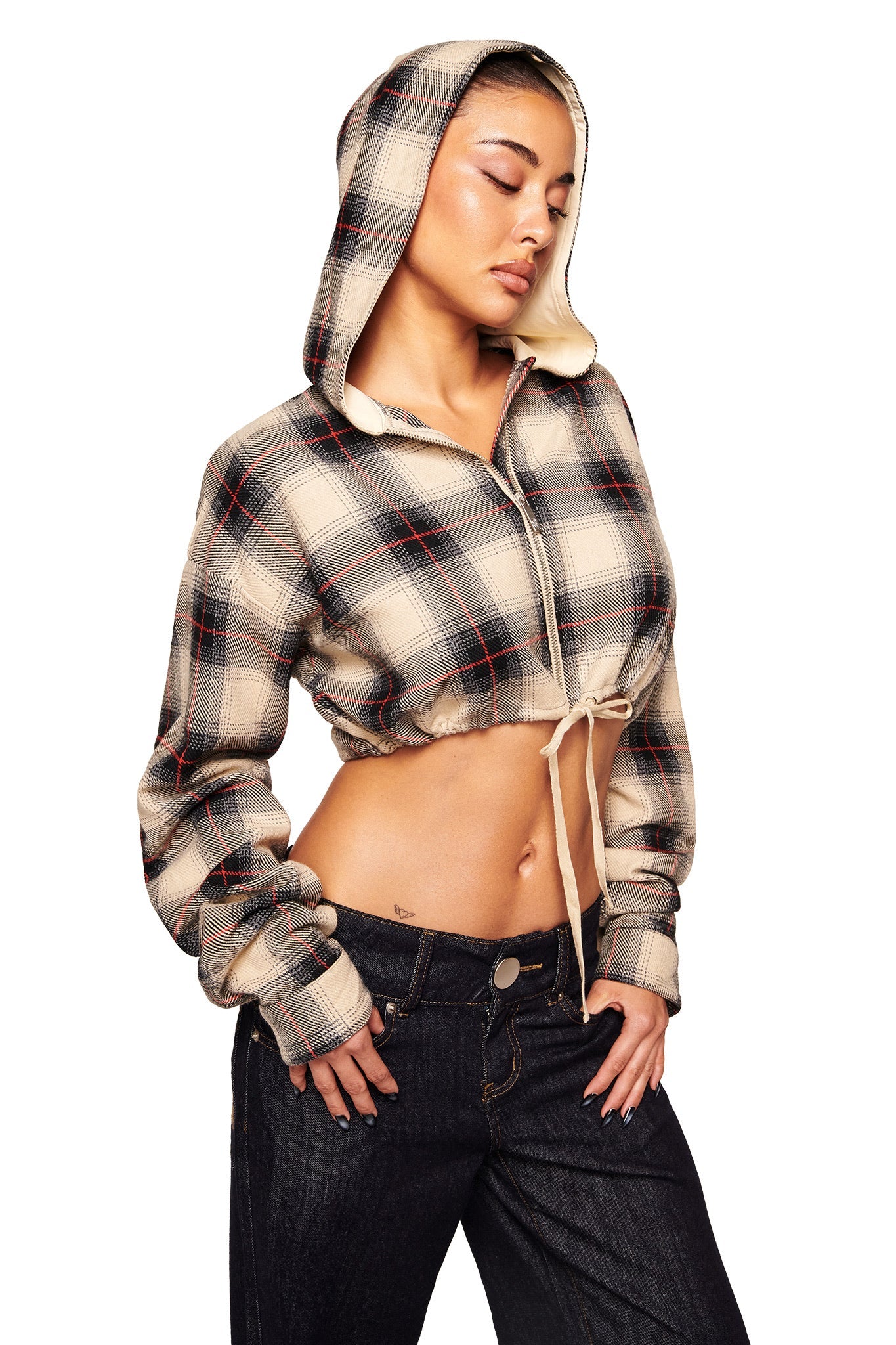 A woman poses in the I.AM.GIA TIFF JACKET - GREY PLAID, styled with the hood up and drawstring, worn as a trendy cropped jacket with dark high-waisted jeans against a white background.