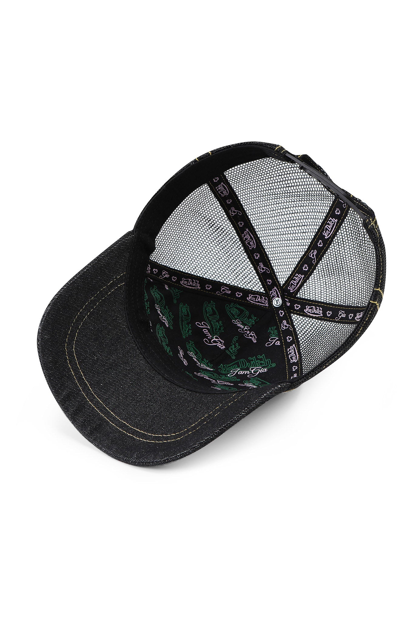 The I.AM.GIA X VON DUTCH TRUCKER HAT - INDIGO DENIM features mesh panels, black seams with white text, inner crown green details, and a curved bill with visible stitching. Brand: I.AM.GIA.