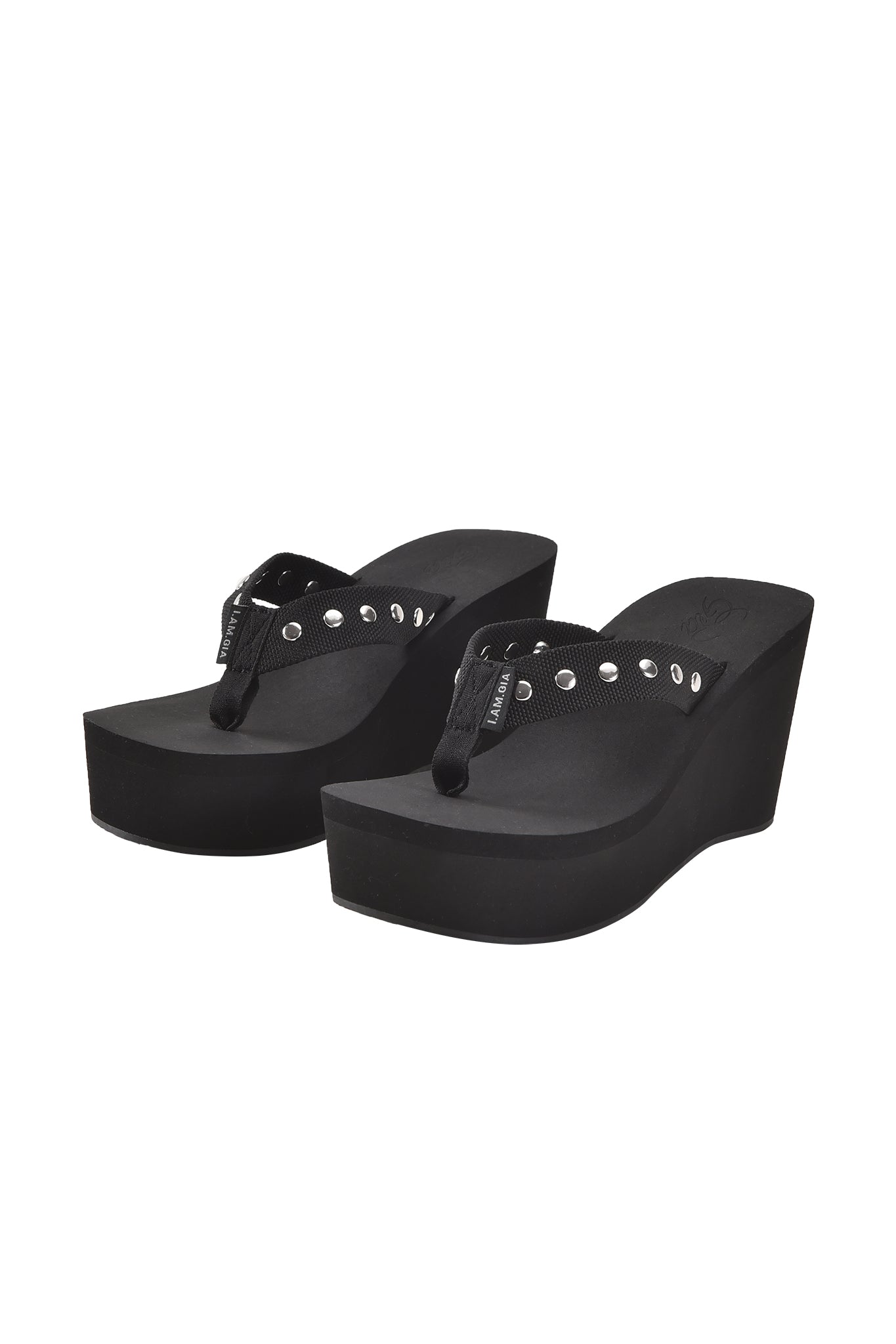 A pair of I.AM.GIA SHELBY STUDDED FLIP FLOP 2.0 in black, featuring studded straps, thick elevated wedge soles, and a classic platform thong design. Shown against a plain white background.