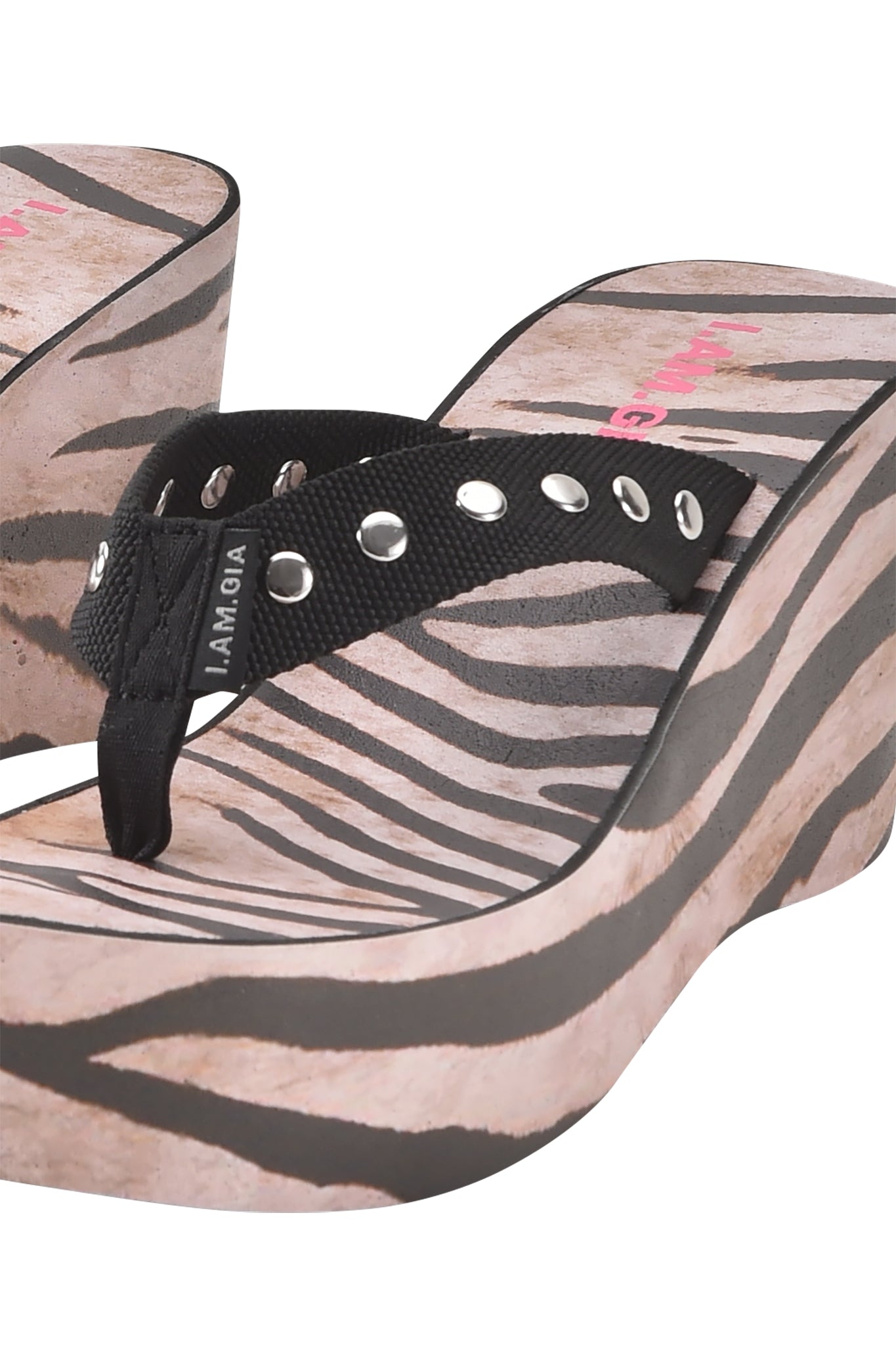 A close-up of I.AM.GIA SHELBY STUDDED FLIP FLOP 2.0 - WILD SIDE sandals with bold zebra print and black straps detailed with silver grommets.
