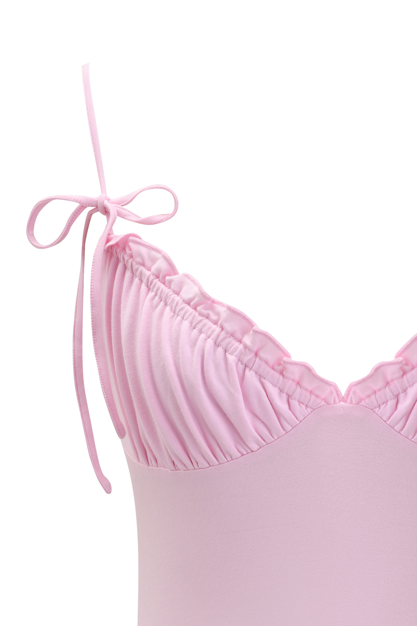 Close-up of the MELANIE CAMI - PINK by I.AM.GIA, a light pink spaghetti strap top featuring ruched bust detailing, adjustable fit, and a decorative bow on the left strap.