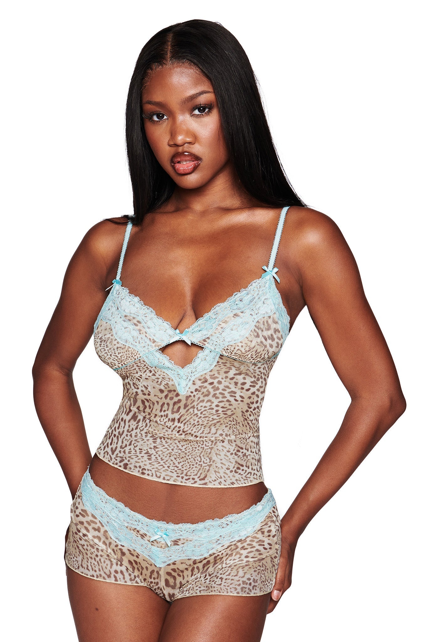 A woman wears the I.AM.GIA TASHA TOP - LEOPARD LIMBO, a leopard print mesh camisole with aqua lace trim, paired with matching shorts. She has long straight hair and a neutral expression against a white background.