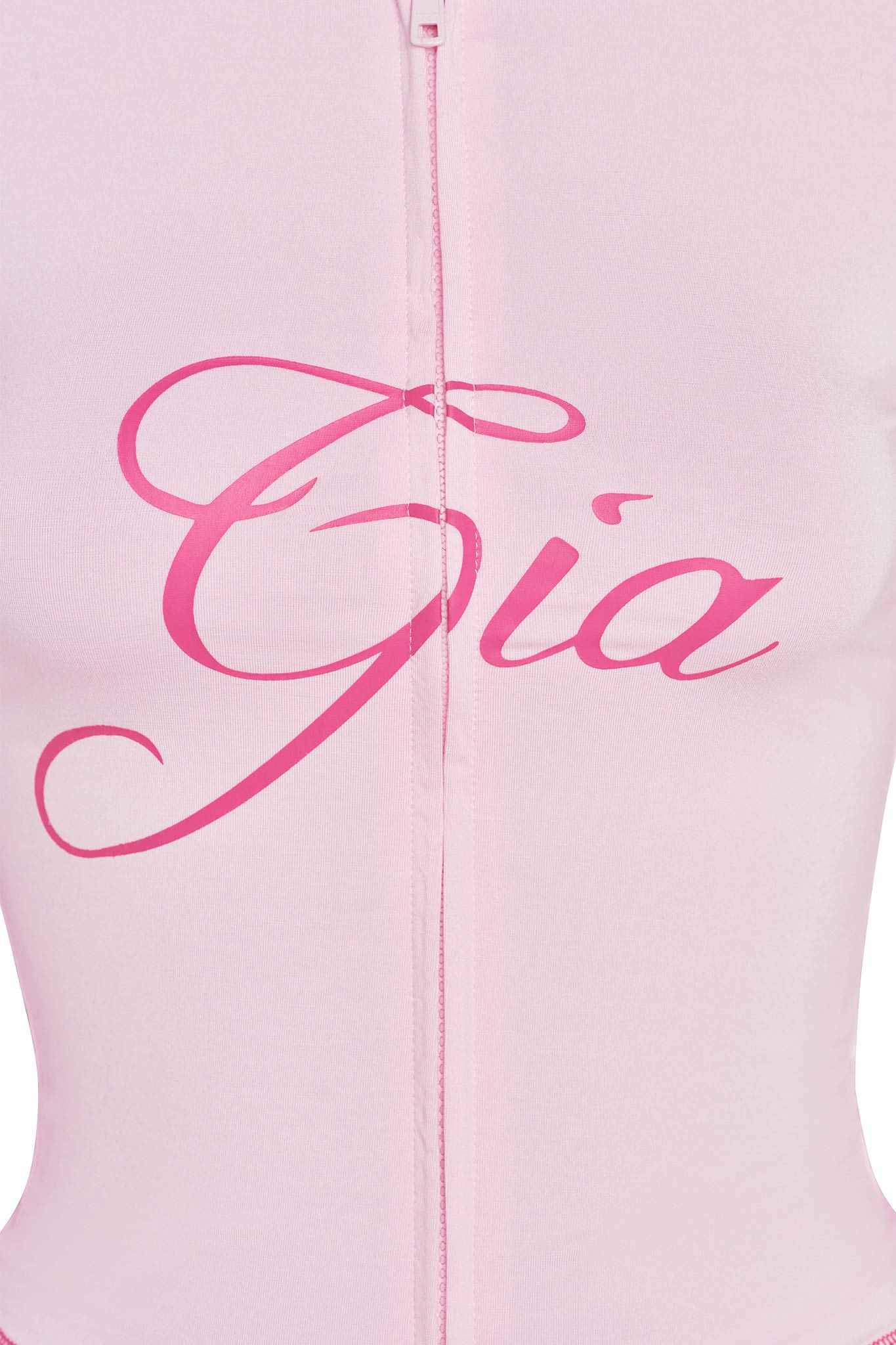 A close-up view of the BLARE HOODIE - PINK : PASTEL PINK garment with the name "Gia" written in large, elegant, cursive letters in a darker shade of pink across the chest area. The piece from I.AM.GIA features a visible zipper running vertically down the center.