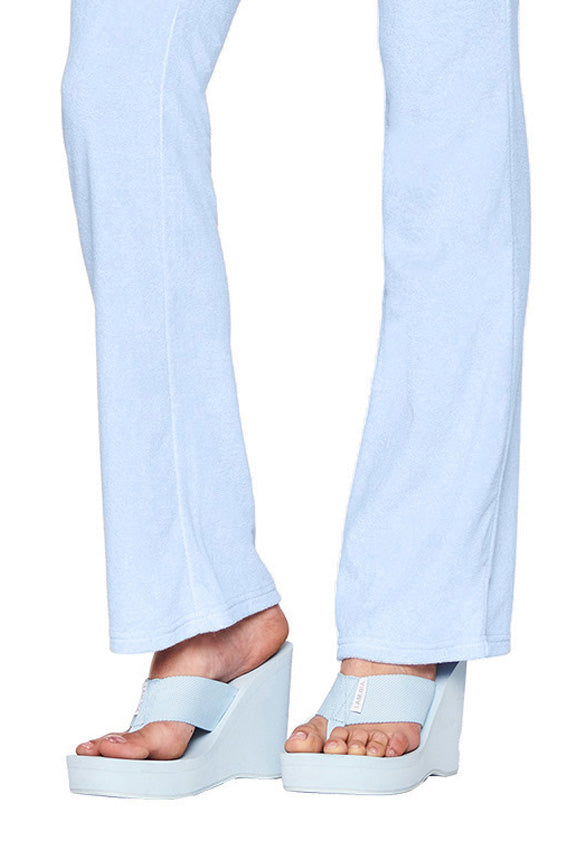A person wearing light blue, wide-legged pants from I.AM.GIA, showing only the lower legs and feet, paired with the SHELBY FLIP FLOP - BLUE: BABY BLUE platform sandals featuring thick soles and open toes.