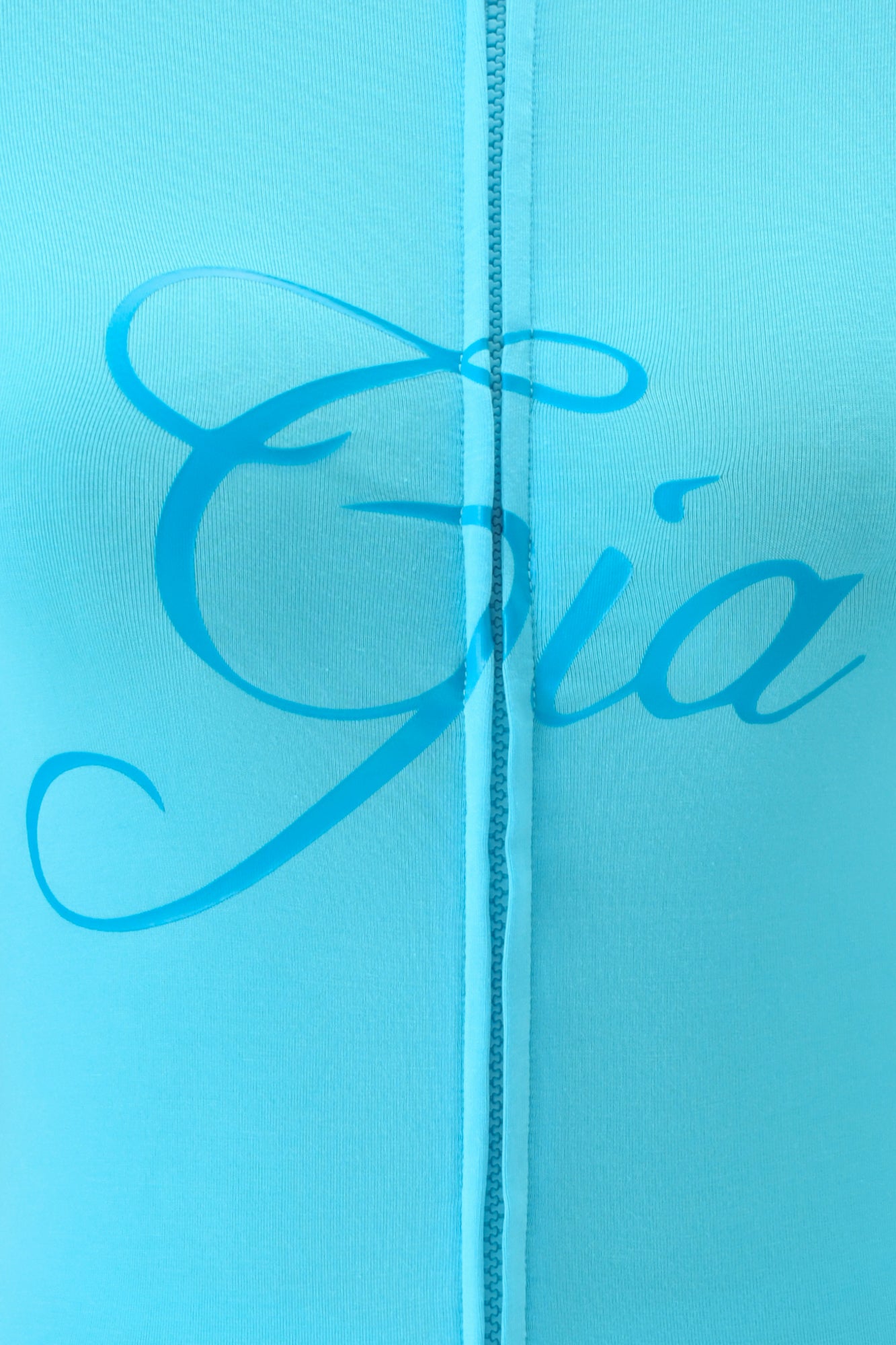 Close-up of neon blue fabric from the I.AM.GIA BLARE HOODIE, featuring “Gia” in elegant script across the center and a vertical stitched seam visible down the middle.