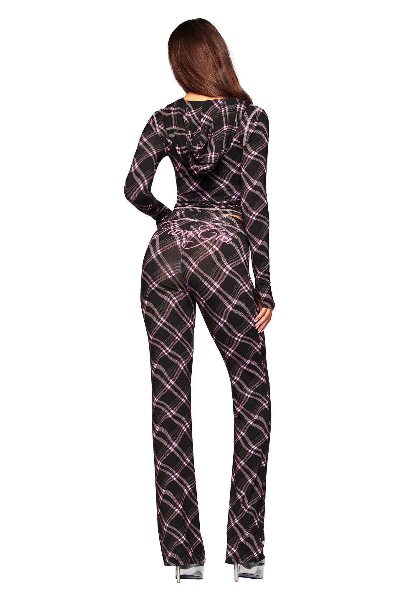 A woman faces away, wearing the I.AM.GIA BLARE HOODIE in black warped plaid with a hood, paired with silver high heels, against a white background.