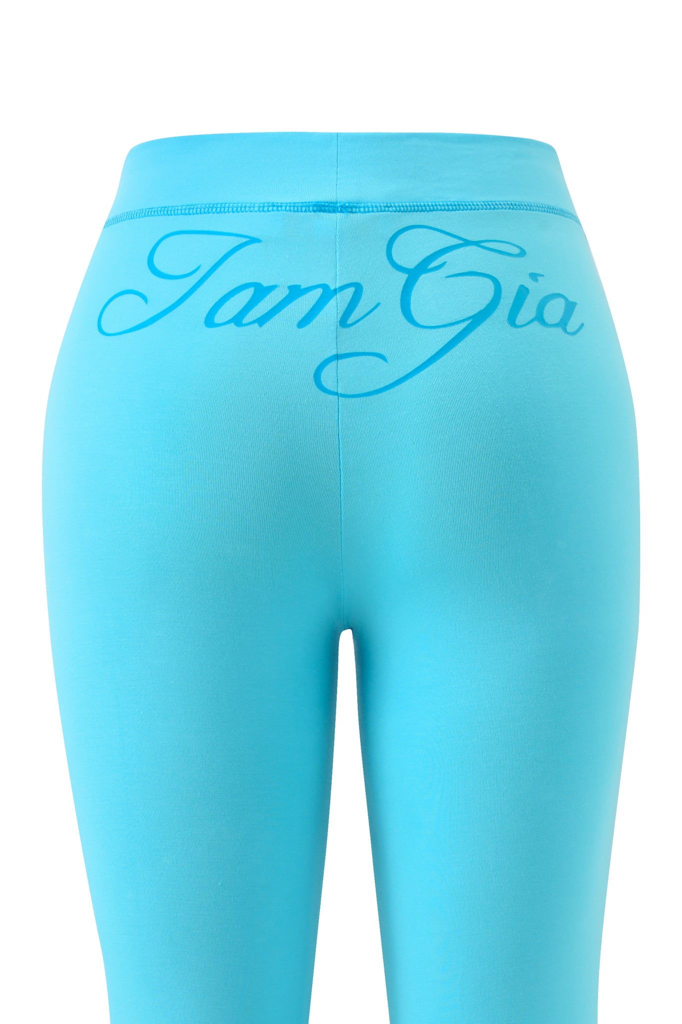 The BLARE TRACKPANT in neon blue by I.AM.GIA is shown from the back, featuring the bold I.AM.GIA logo in large cursive script across the waistband against a plain white background.