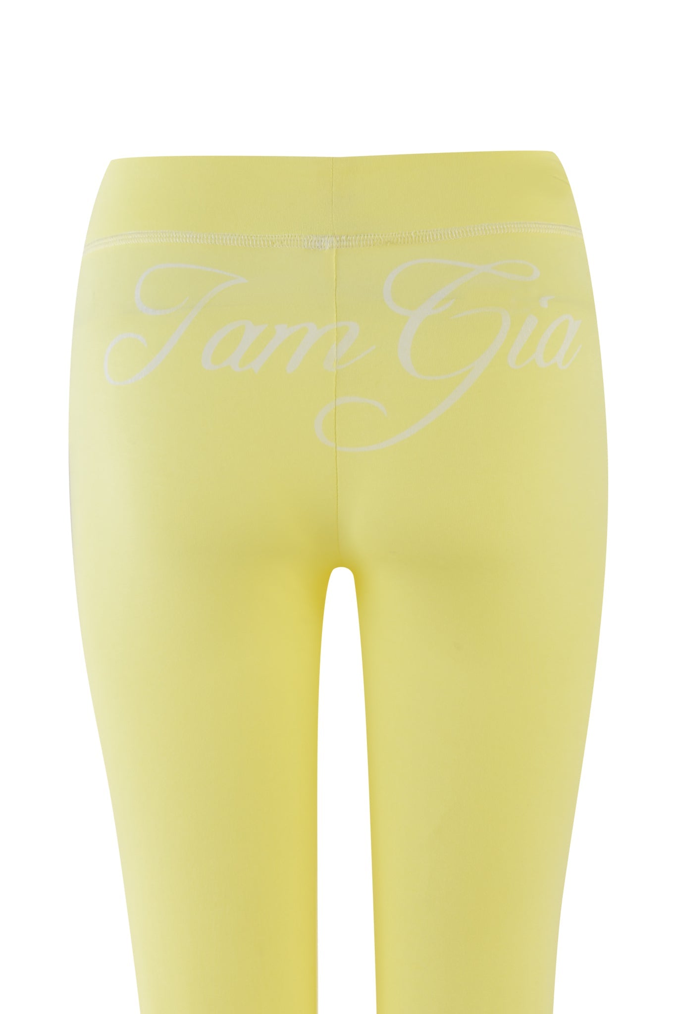 The BLARE TRACKPANT - YELLOW by I.AM.GIA features a close-up of the back with the brand's signature logo in white script. Made from bamboo and jersey, these pale yellow leggings offer style and comfort against a plain white background.