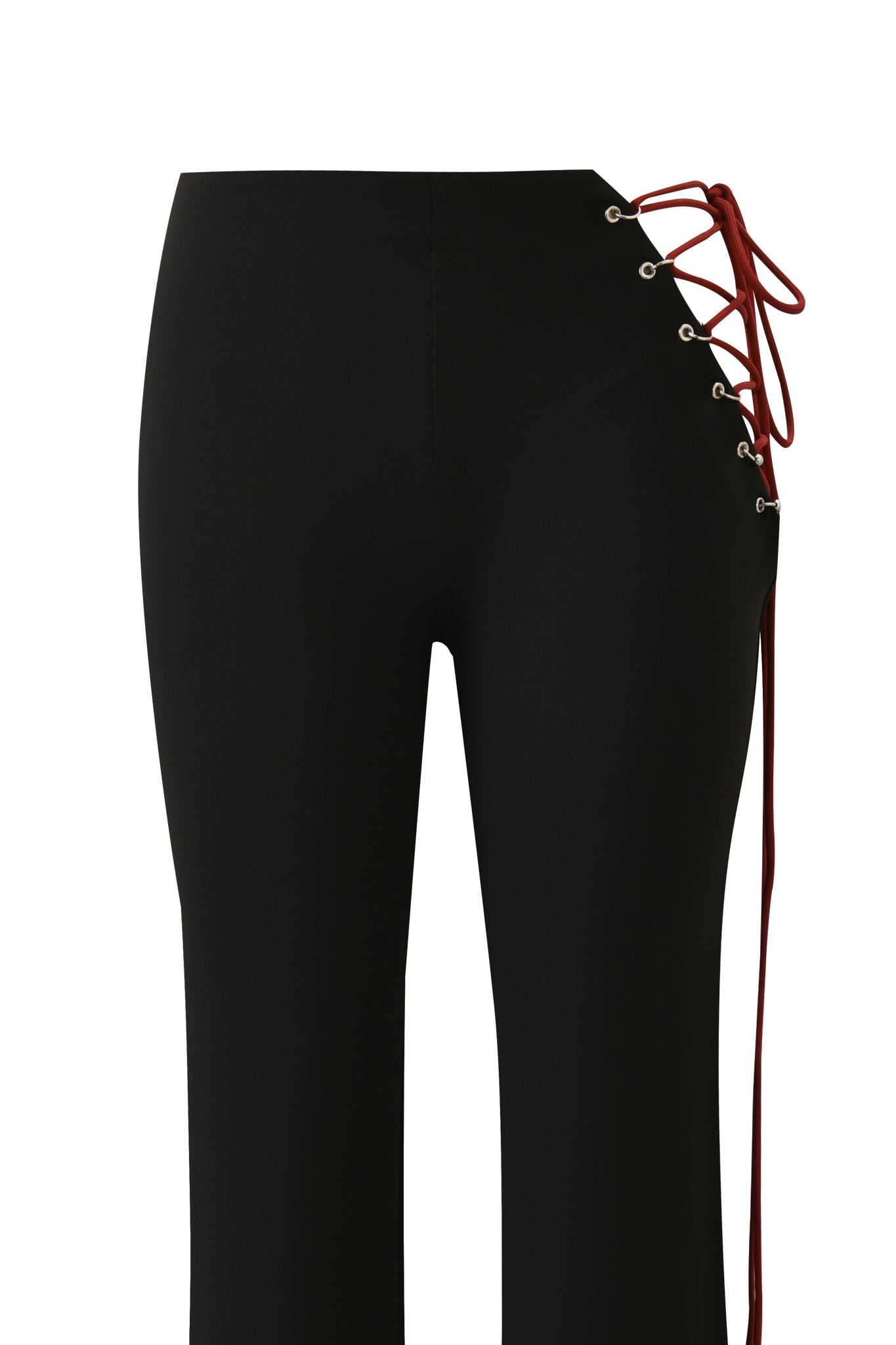 The ONYX PANT - BLACK by I.AM.GIA features a fitted waist, wide legs, silver eyelets, and a red lace-up detail threaded diagonally through the right cutout hip with laces hanging loosely down the side.
