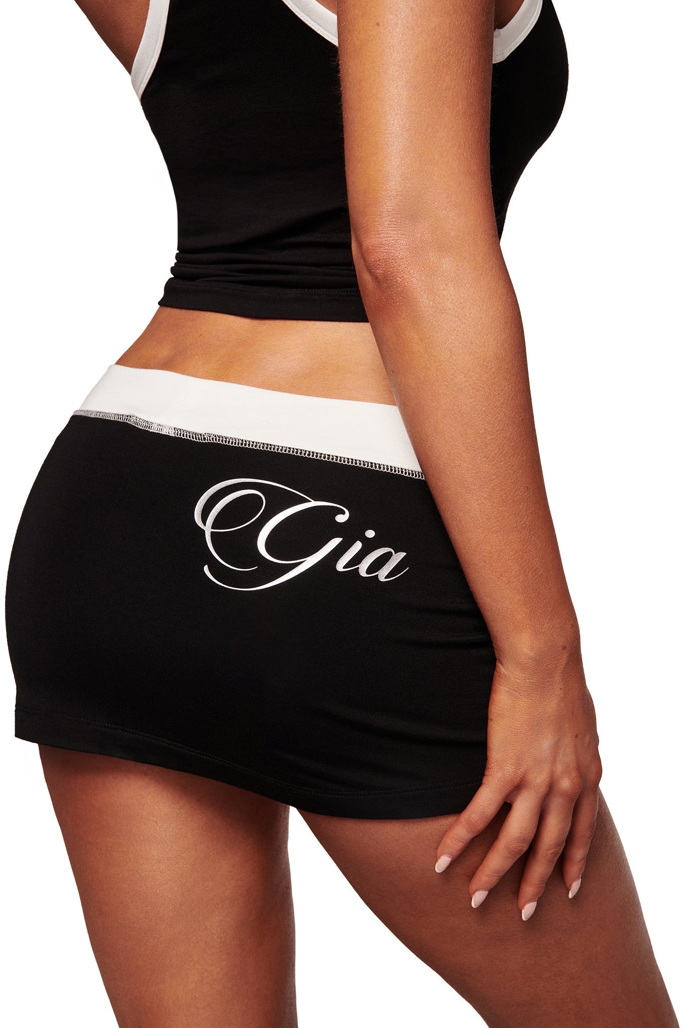 A person wears the BLARE MICRO SKORT in black and white by I.AM.GIA, featuring buttery-soft viscose fabric and "Gia" written in white script on the back.