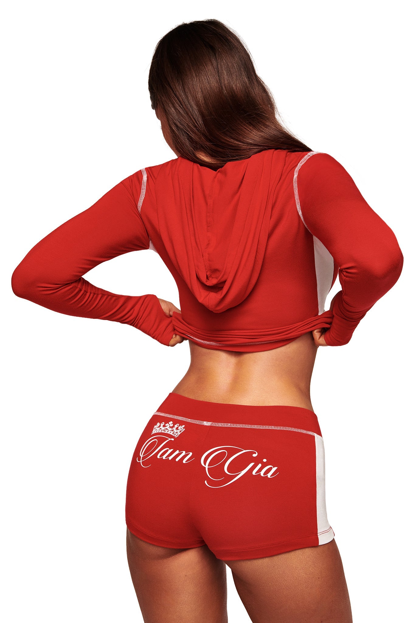 A woman with long brown hair, seen from behind, wears a red hooded crop top and I.AM.GIA BLARE PANELLED SHORT - RED, featuring sporty white trim and the brand's logo on the back.