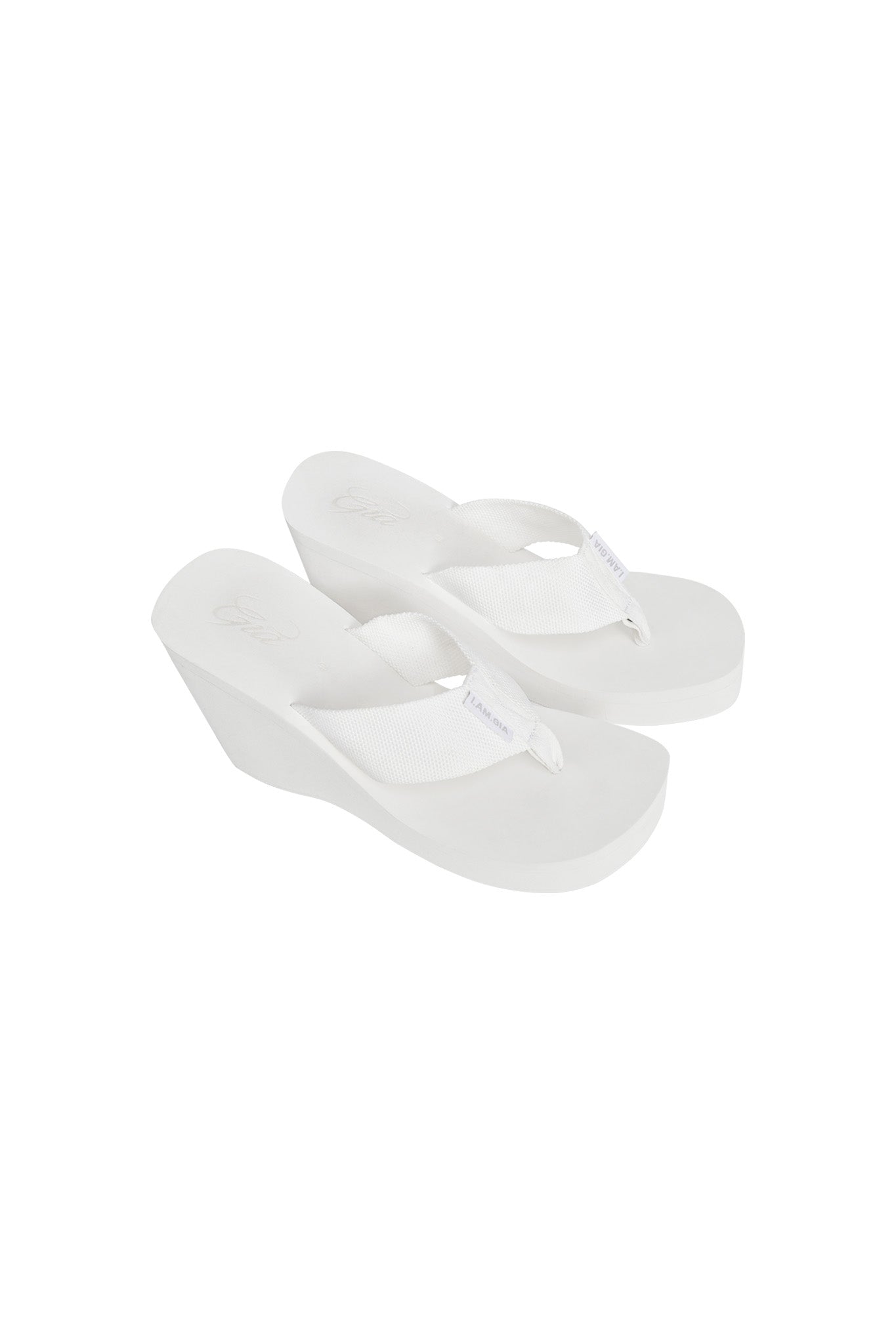 The SHELBY FLIP FLOP - WHITE by I.AM.GIA features wedge heels and wide fabric straps. The seamless color of the soles and straps creates a clean, uniform look designed for casual and comfortable wear.