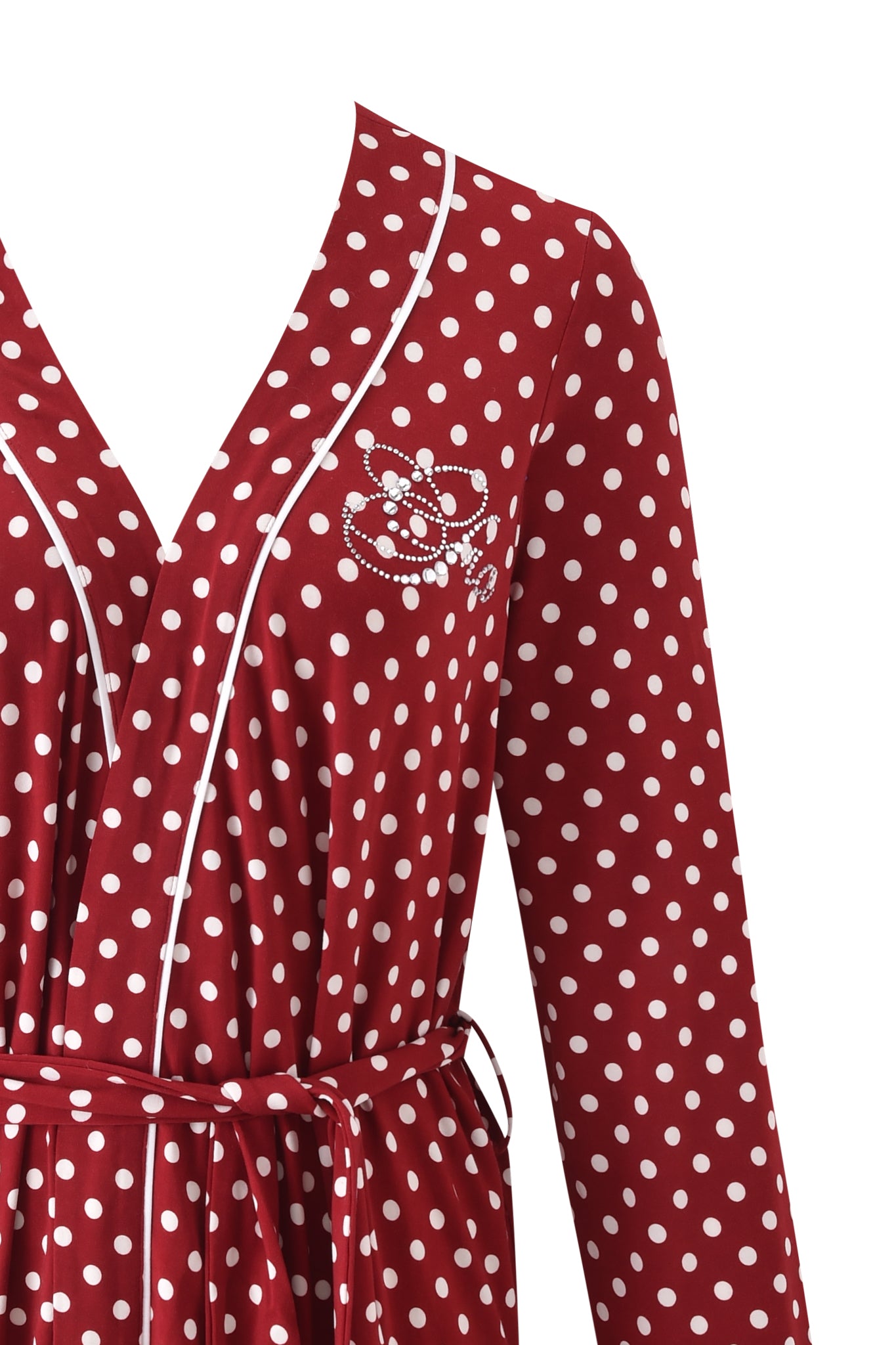 A close-up of the MELANIE SLEEPWEAR - RED POLKA DOT by I.AM.GIA, featuring a red polka dot print, long sleeves, white piping on the neckline, a fabric belt, and embroidered detail on the chest.