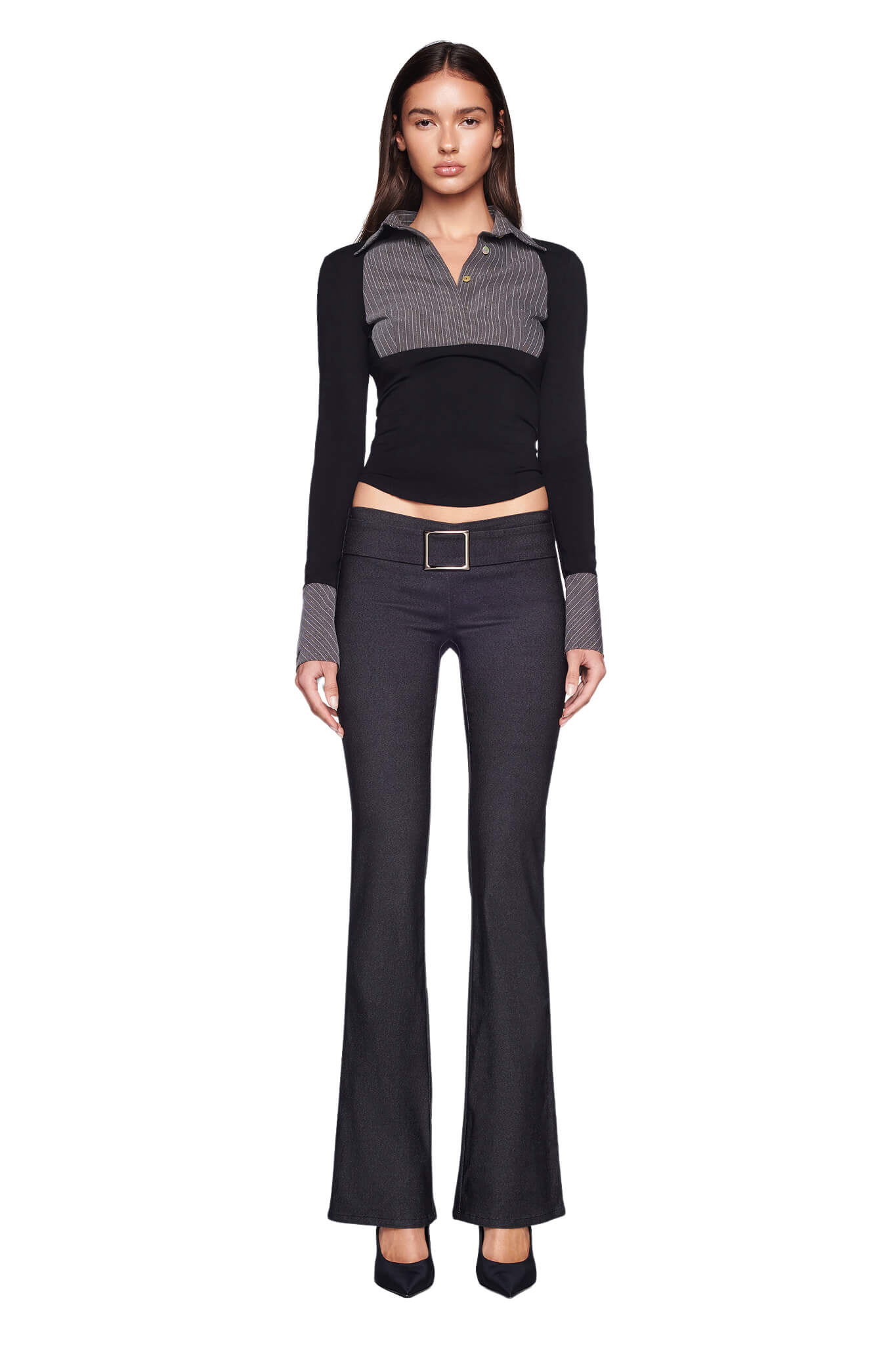 A woman with long dark hair stands against a plain white background, wearing the SHARAH TOP - BLACK : GREY by I.AM.GIA along with matching high-waisted pants featuring a rectangular buckle. She completes her outfit with black pointed-toe shoes.