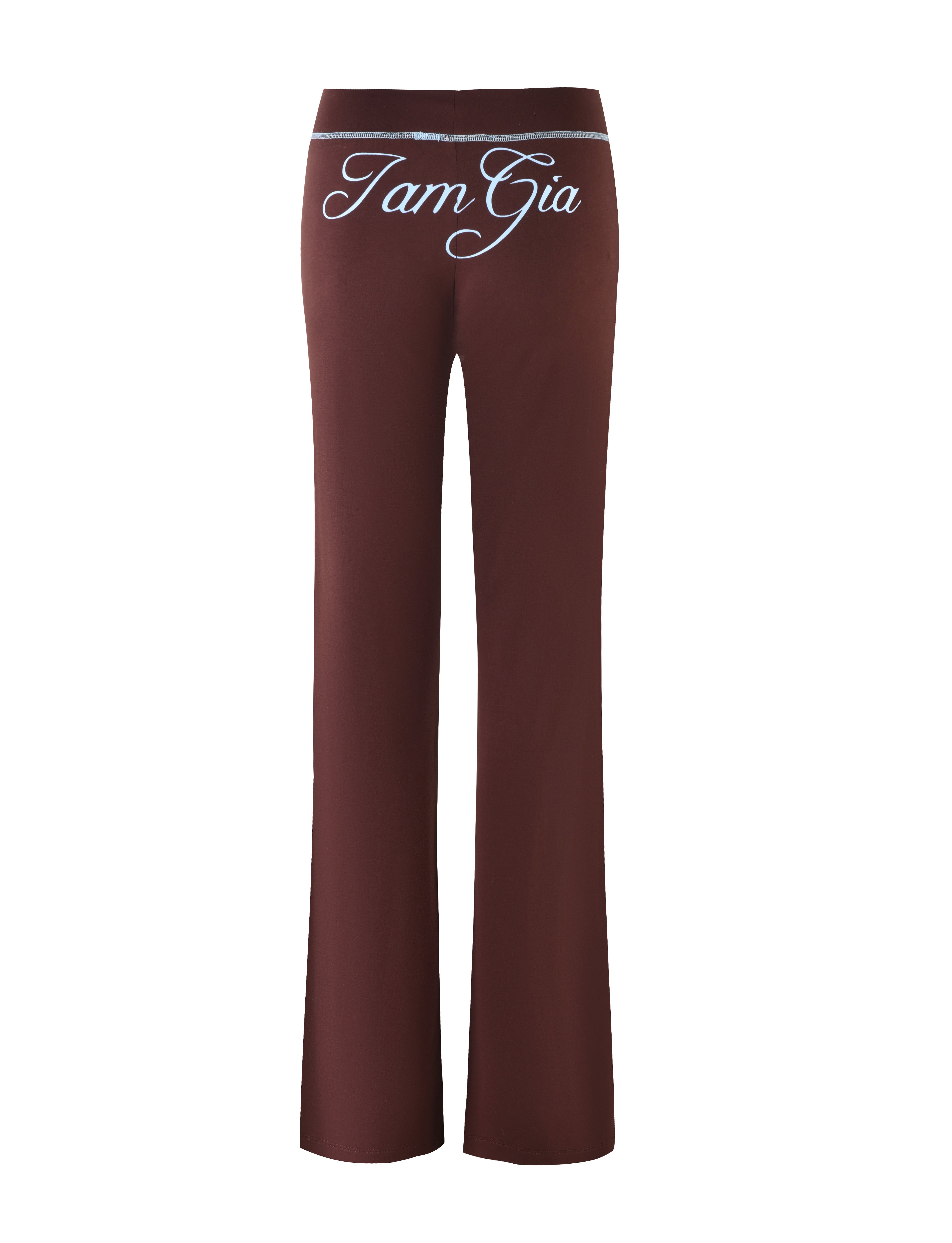 The BLARE TRACKPANT - BROWN is shown from the back, displaying the brand name "I.AM.GIA" in white script at the waistband. The pants feature a straight leg cut and a smooth, minimalist design.