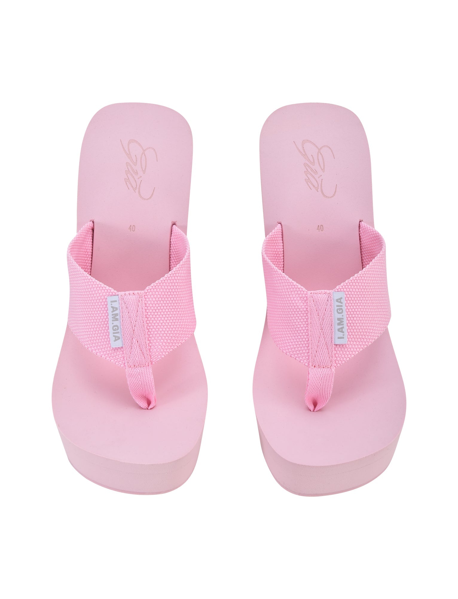 A pair of the SHELBY FLIP FLOP - PINK : BABY PINK from I.AM.GIA, featuring thick, textured straps subtly branded with a small white I.AM.GIA tag on each strap. These pink platform flip-flops come with a cushioned insole and a slightly elevated sole. The footbeds also display the brand's logo and size marking.